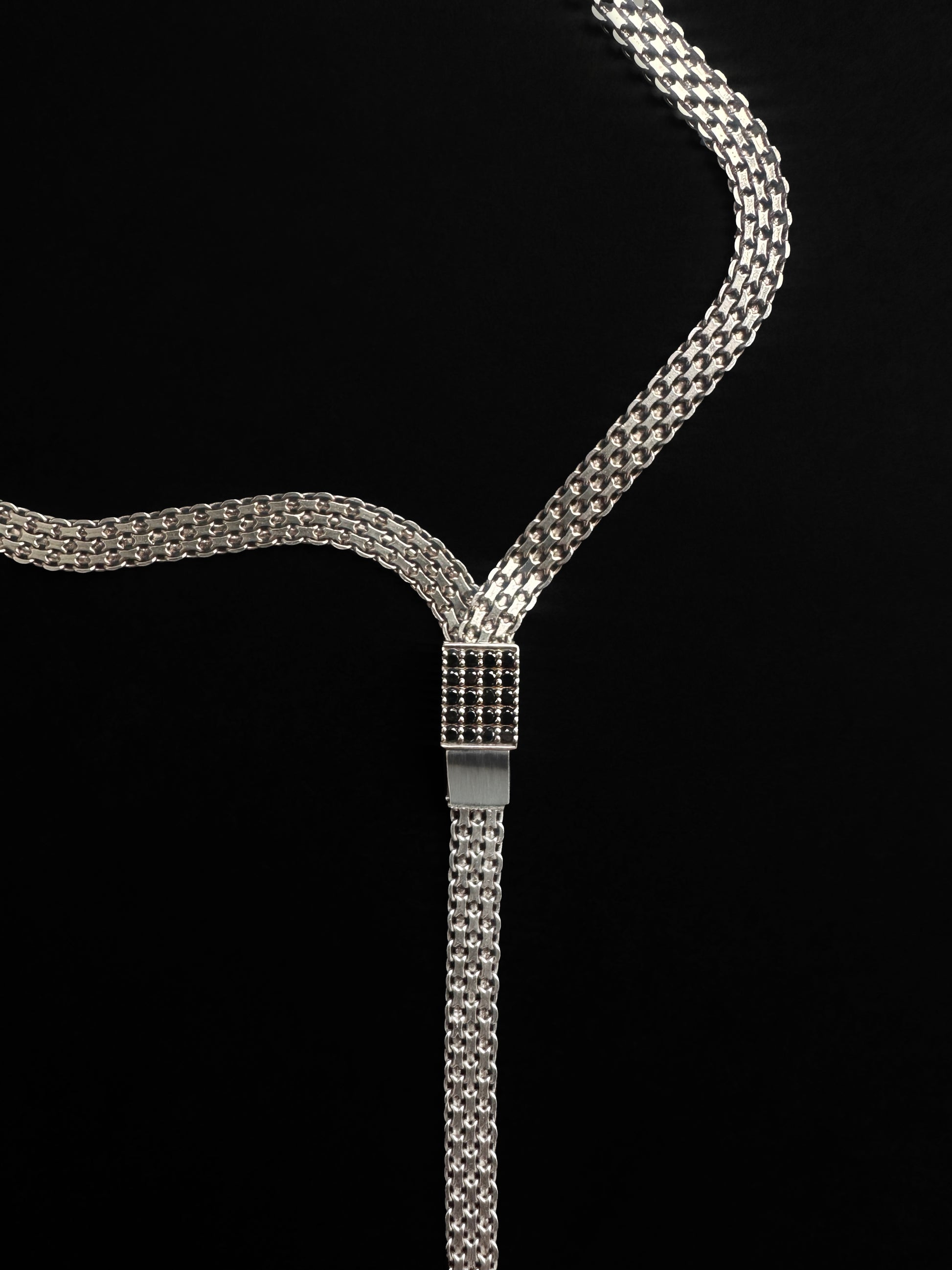 A sterling silver necklace with a polished finish featuring a tie-inspired silhouette and black diamond pavé.
