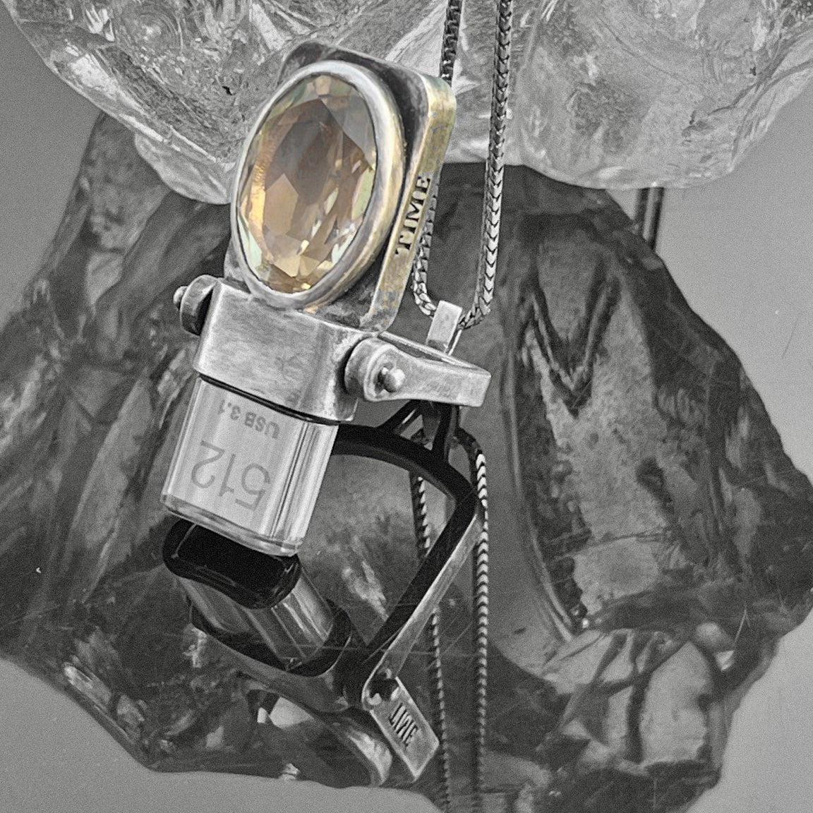 Side view of the sterling silver USB Drives Necklace with champagne citrine displayed against textured glass.